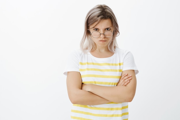 Ritratto di ragazza bionda indignata biasimevole con gli occhiali in posa in studio