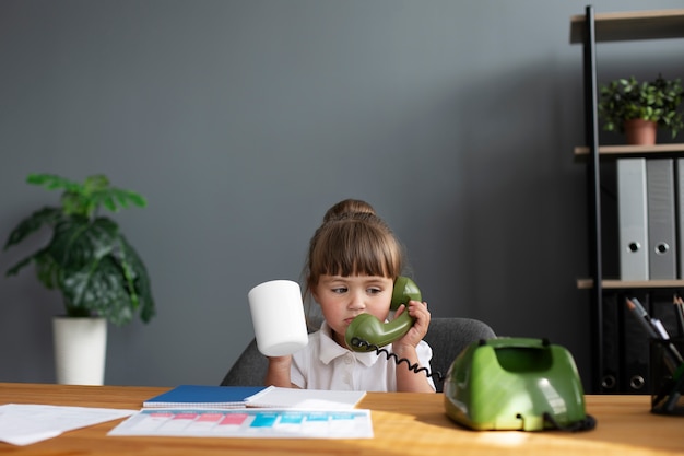 Ritratto di ragazza carina parlando al telefono rotante in ufficio