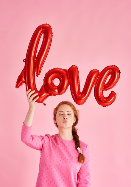 Ritratto di ragazza che soffia un bacio e tiene in mano un palloncino