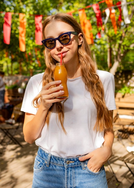 Ritratto di ragazza con bottiglia di succo fresco nel parco