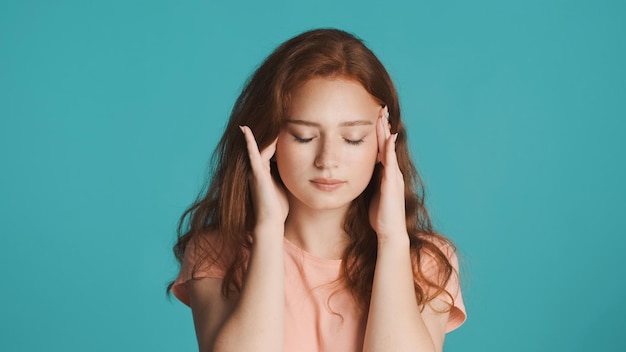 Ritratto di ragazza rossa sconvolta che mostra mal di testa sulla fotocamera su sfondo colorato Espressione stanca