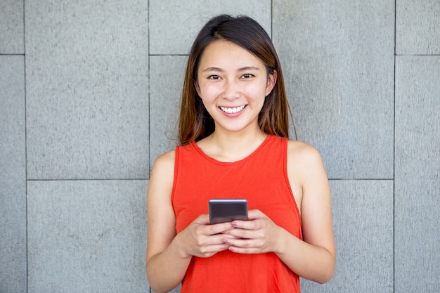 Ritratto di ragazza sorridente asiatica con il telefono cellulare