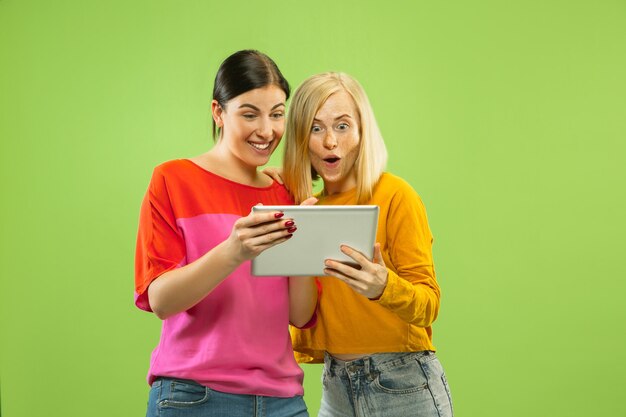 Ritratto di ragazze abbastanza affascinanti in abiti casual isolato sulla parete verde dello studio