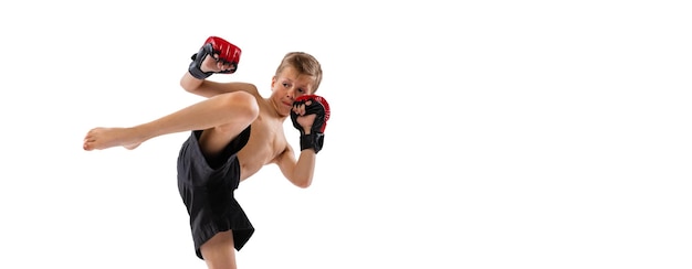 Ritratto di ragazzino in formazione uniforme che pratica la boxe tailandese su sfondo bianco per studio