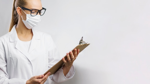 Ritratto di ricercatrice in laboratorio con maschera medica e appunti