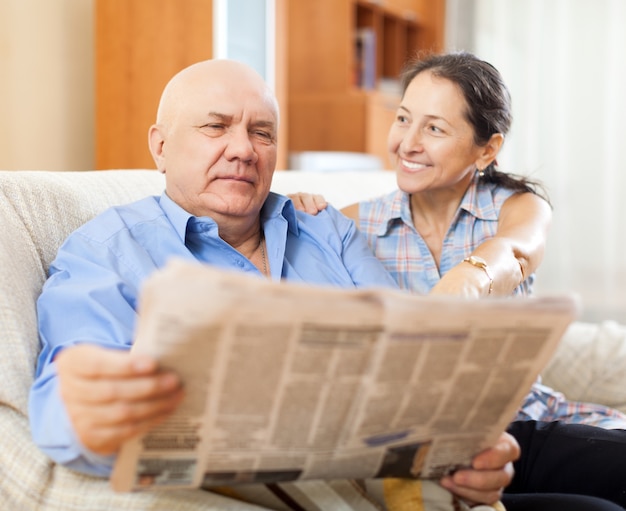Ritratto di ridere donna matura e uomo anziano con il giornale
