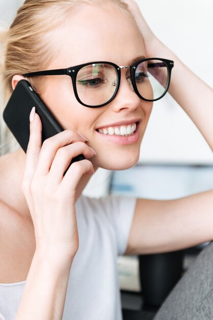 Ritratto di signora bionda sorridente che parla sullo smartphone