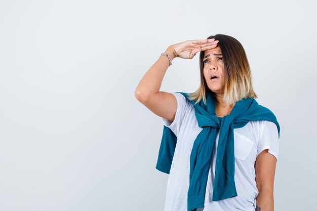 Ritratto di signora con un maglione legato che guarda lontano con la mano sopra la testa in una maglietta bianca e che sembra una vista frontale focalizzata