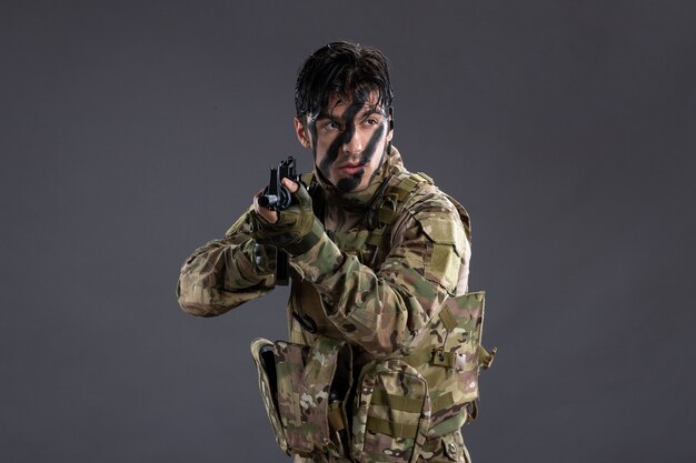 Ritratto di soldato coraggioso in mimetica con mitragliatrice sul muro scuro