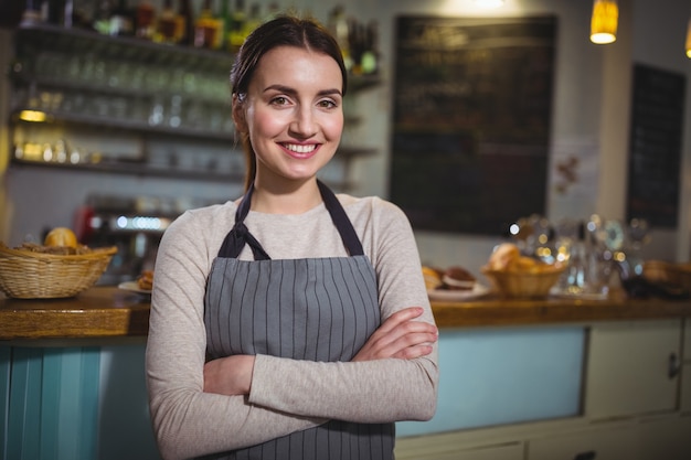 Ritratto di sorridente cameriera in piedi al banco