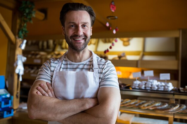 Ritratto di sorridere proprietario in piedi nel negozio di panetteria