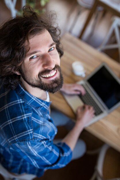 Ritratto di sorridere uomo con laptop in caffetteria