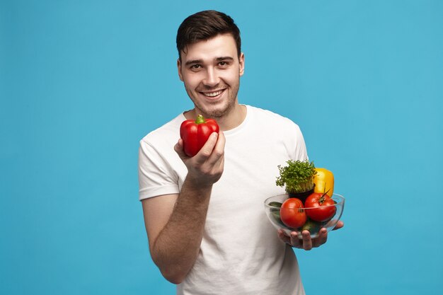 Ritratto di t-shirt bianca da portare del giovane uomo caucasico dai capelli scuro muscolare sveglio