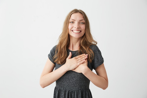 Ritratto di tenera ragazza felice sorridente sorridendo per mano sul cuore.