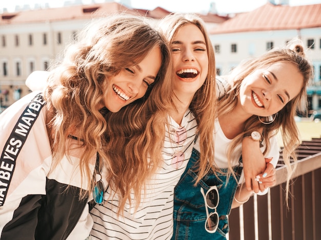 Ritratto di tre giovani belle ragazze sorridenti hipster in abiti estivi alla moda. Donne spensierate sexy che posano per strada. Divertimento dei modelli positivi