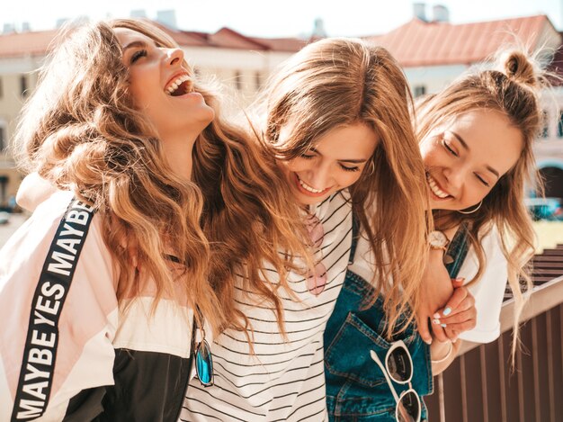 Ritratto di tre giovani belle ragazze sorridenti hipster in abiti estivi alla moda. Donne spensierate sexy che posano per strada. Divertimento dei modelli positivi