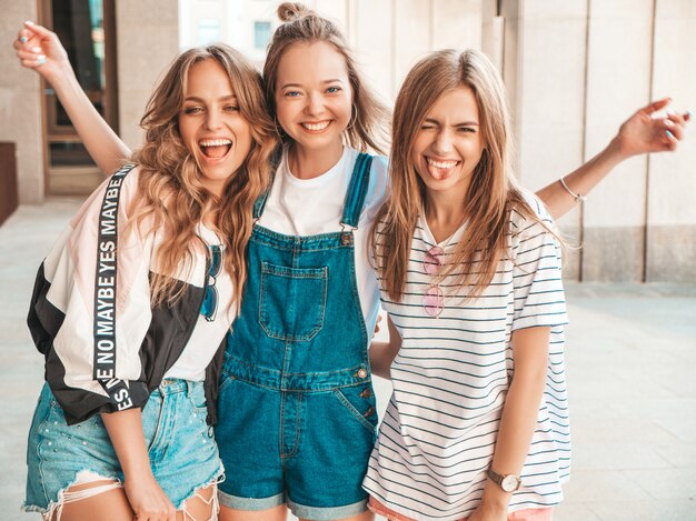 Ritratto di tre giovani belle ragazze sorridenti hipster in abiti estivi alla moda. Donne spensierate sexy che posano per strada. Divertimento dei modelli positivi