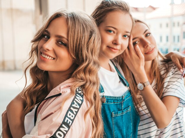 Ritratto di tre giovani belle ragazze sorridenti hipster in abiti estivi alla moda. Donne spensierate sexy che posano per strada. Divertimento dei modelli positivi