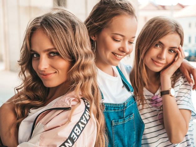 Ritratto di tre giovani belle ragazze sorridenti hipster in abiti estivi alla moda. Donne spensierate sexy in posa sulla strada. Divertimento di modelli positivi