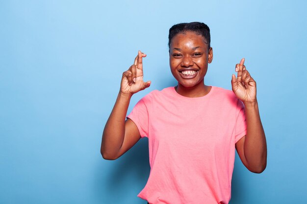 Ritratto di un adolescente afroamericano sorridente che tiene le dita incrociate