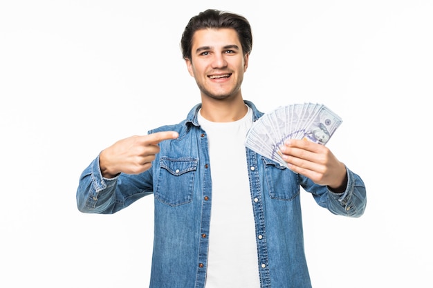 Ritratto di un allegro uomo di successo in camicia bianca che mostra un mucchio di banconote in due mani mentre sta in piedi e celebra isolato su bianco