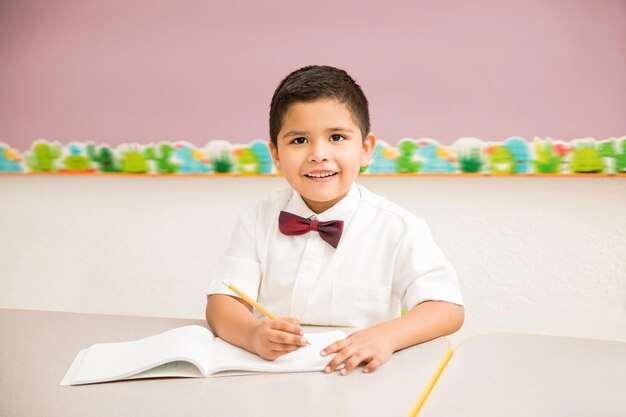 Ritratto di un bel bambino ispanico che indossa un'uniforme e si diverte a lezione in età prescolare