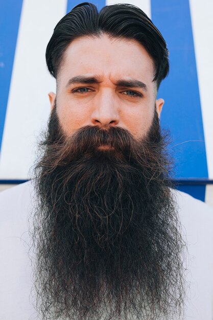 Ritratto di un bel giovane con la barba lunga che guarda l&#39;obbiettivo