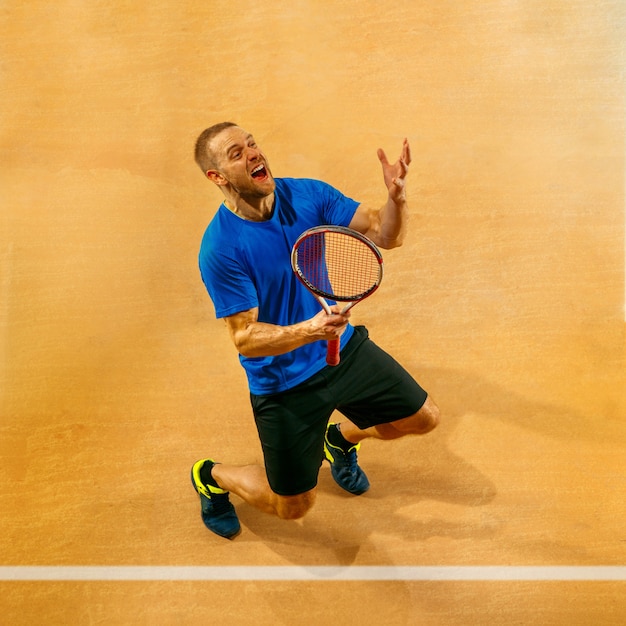 Ritratto di un giocatore di tennis maschio bello che celebra il suo successo su una parete della corte. Emozioni umane, vincitore, sport, concetto di vittoria