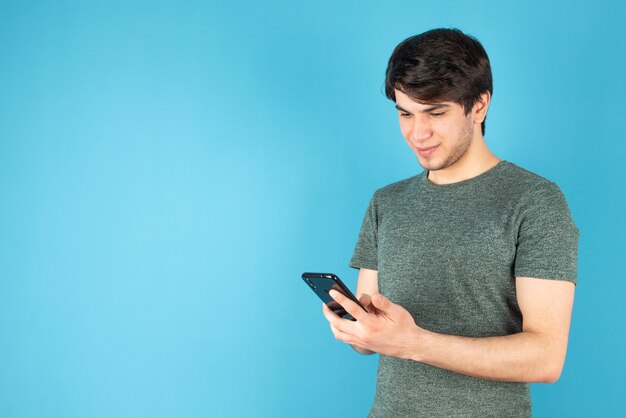 Ritratto di un giovane che utilizza un telefono cellulare contro il blu.