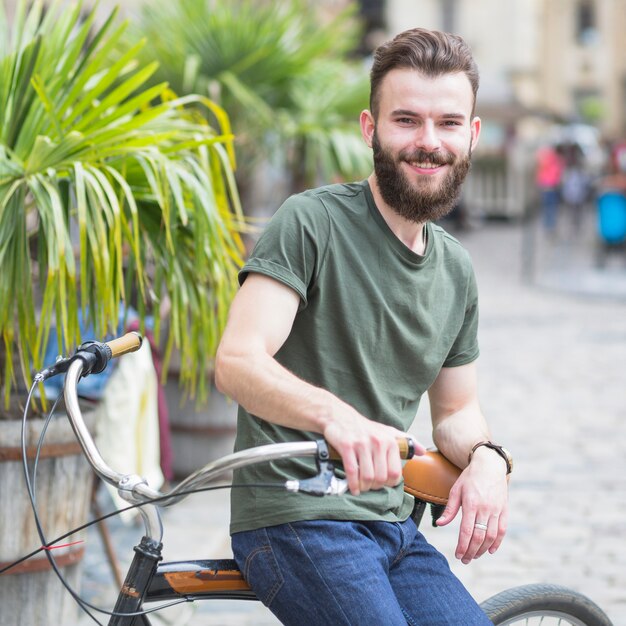 Ritratto di un giovane ciclista maschio barbuto seduto sulla bicicletta