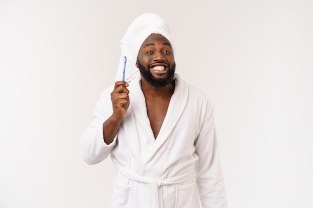 Ritratto di un giovane darkanm felice che si lava i denti con un dentifricio nero su sfondo bianco