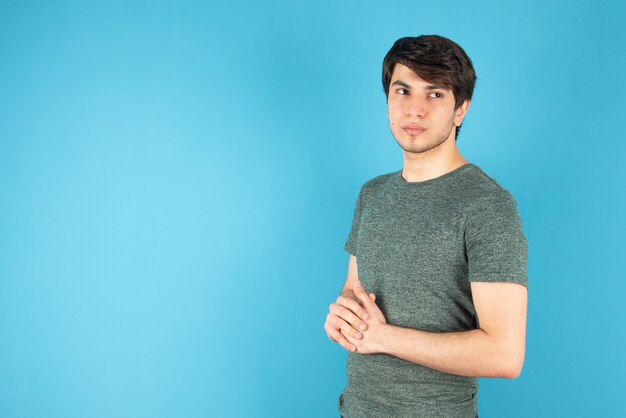 Ritratto di un giovane in piedi contro il blu.