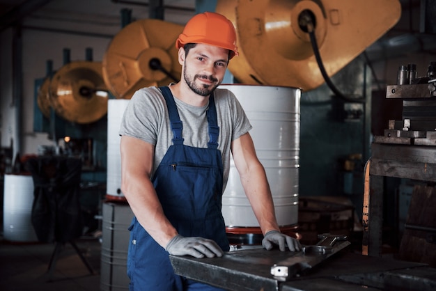 Ritratto di un giovane operaio in un cappello duro in un grande impianto di lavorazione dei metalli.