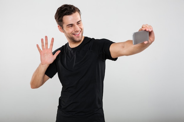 Ritratto di un giovane ragazzo sorridente agitando la fotocamera