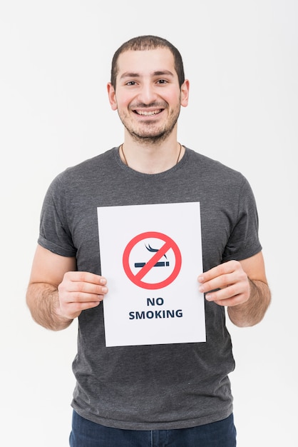 Ritratto di un giovane sorridente che mostra segno non fumatori isolato su sfondo bianco