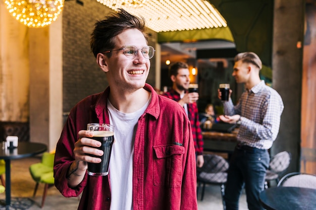Ritratto di un giovane sorridente tenendo il bicchiere di birra godendo