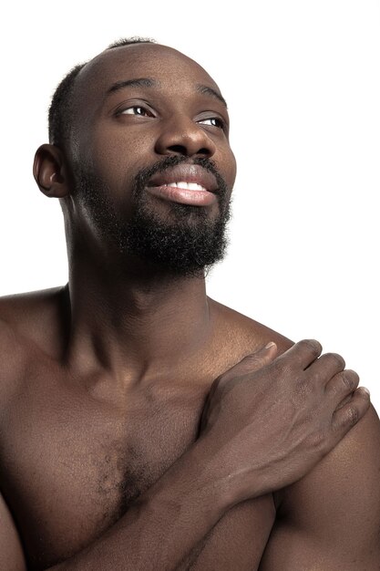 Ritratto di un giovane uomo africano sorridente felice nudo in studio.