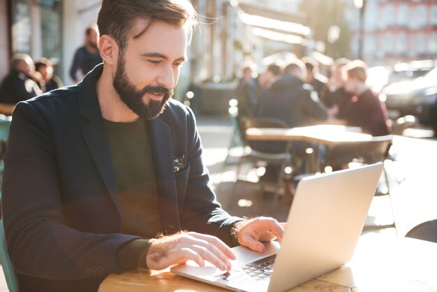 Ritratto di un giovane uomo alla moda che lavora al computer portatile