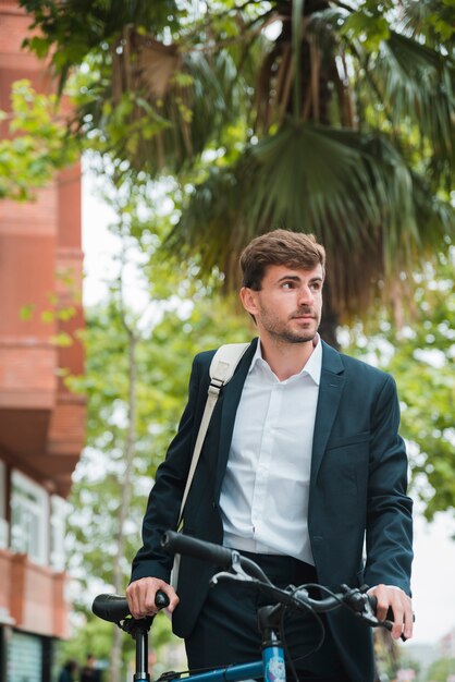 Ritratto di un giovane uomo d&#39;affari con la sua bicicletta guardando lontano