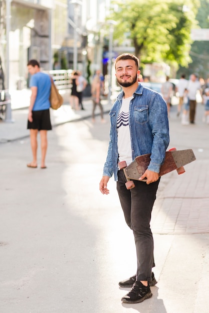 Ritratto di un giovane uomo felice con skateboard