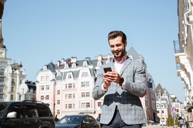 Ritratto di un giovane uomo in giacca utilizzando il telefono cellulare