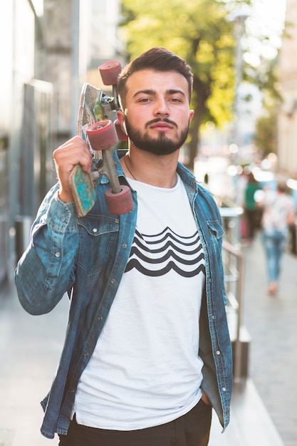 Ritratto di un maschio skateboarder con skateboard