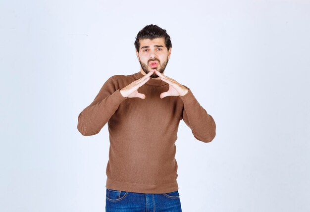 Ritratto di un modello di giovane uomo bello in piedi e in posa con le mani su sfondo bianco. Foto di alta qualità