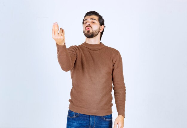 Ritratto di un modello di giovane uomo con barba in piedi e in posa con le mani. Foto di alta qualità