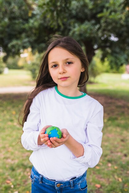 Ritratto di un mondo adorabile del pianeta dell&#39;argilla della tenuta della ragazza in parco