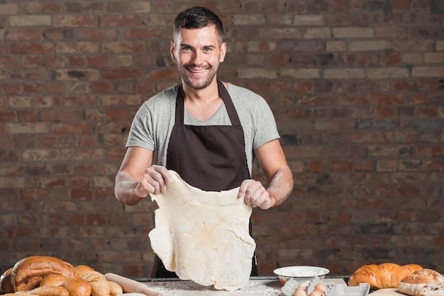 Ritratto di un panettiere maschio sorridente che prepara pane in forno