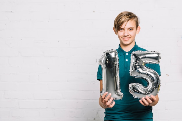 Ritratto di un ragazzo sorridente che mostra il numero 15 pallone aerostatico