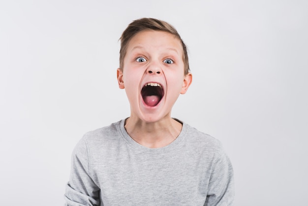 Ritratto di un ragazzo urlando rumorosamente contro sfondo grigio
