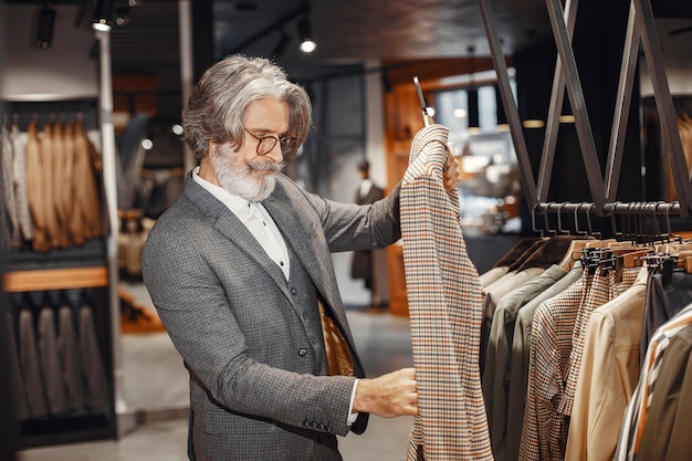 Ritratto di un ricco uomo maturo. Senior visitando una boutique di moda. Il maschio acquista un nuovo costume esclusivo.