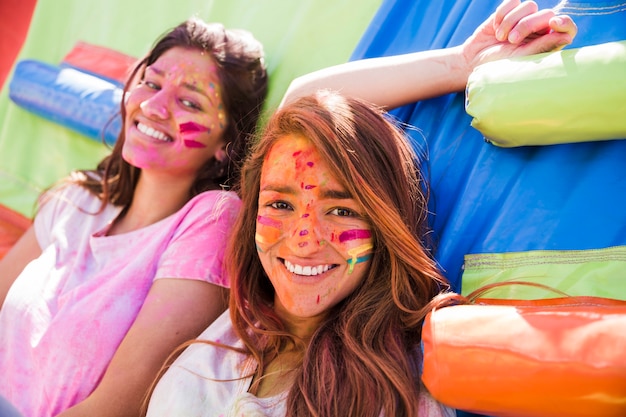 Ritratto di un sorridente due giovani donne con la faccia di colore holi